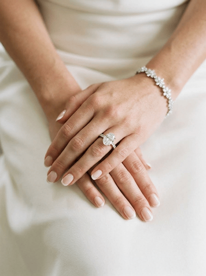 Bride hands wearing diamond engagement ring and floral bracelet